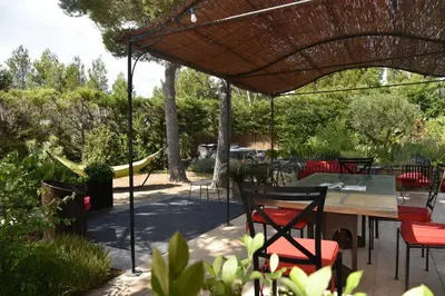 a patio with a table and chairs under a roof at magnificent detached villa with heated swimming pool and jacuzzi, in aureille, in the alpilles – 8 people in Aureille