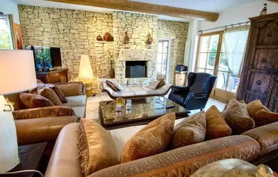 a living room with couches and a stone wall at Évasion Provençale : Villa Élégante pour 10 Personnes in Villars