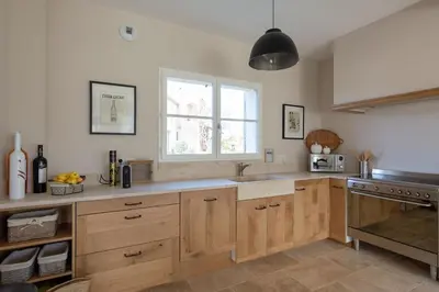 a kitchen with wooden cabinets and a sink and a window at Bastide la Melonnerie in Lacoste