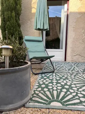 a chair and an umbrella on a patio at Sasha'blue-terrasse jardin-park-clim-piscine in LʼIsle-sur-la-Sorgue