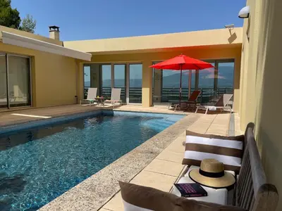 a swimming pool with a red umbrella and chairs at La Beaume in Blauvac