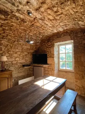 a dining room with a wooden table and a window at Les Grottes in Sivergues