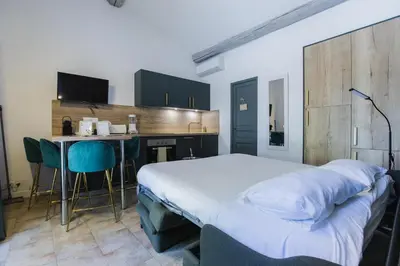 a bedroom with a bed and a kitchen with a table at Gîte Petit Luberon chez Manon en Luberon - Vacation rental in guest house in Lagnes