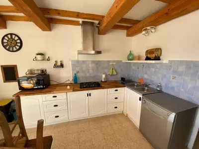 a kitchen with white cabinets and a stainless steel refrigerator at Gîte Lou Pastre in Aureille