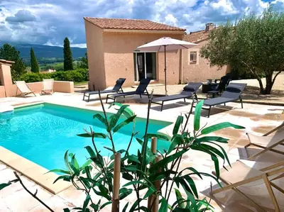 a swimming pool with chairs and a villa at Mas Moucia in Mormoiron