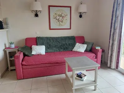 a living room with a red couch and a table at Maison 3 pièces domaine golf Pont Royal in Mallemort