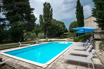 a swimming pool with chairs and an umbrella at Le Mas de Jalique - Isle-sur-la-Sorgue in LʼIsle-sur-la-Sorgue