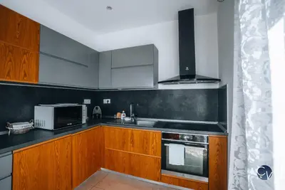 a kitchen with wooden cabinets and a stove top oven at Villa Moderne avec Jacuzzi proche d'Avignon in Le Thor
