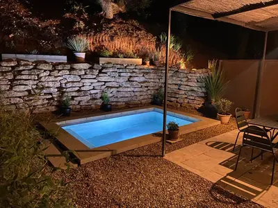 a swimming pool in a yard with a stone wall at Mas du Clos , Tilleul in Roussillon