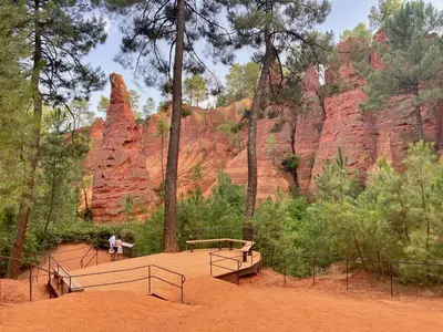 a person sitting on a bench in front of red rocks at Mas du Clos , Tilleul in Roussillon