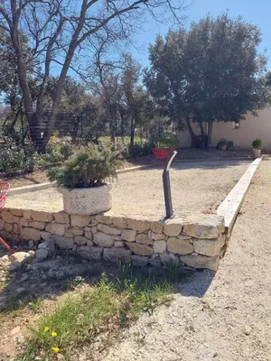 a stone wall with a bench in a yard at Gîte Bienvenue Chez Nous in Ménerbes