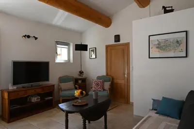 a living room with a tv and a table and chairs at Gîte Bienvenue Chez Nous in Ménerbes