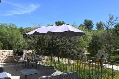 a patio with an umbrella and a table and chairs at Gîte Bienvenue Chez Nous in Ménerbes