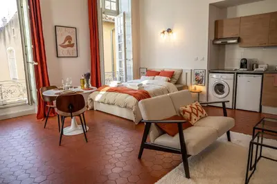 a bedroom with a bed and a table and a kitchen at Superbe appartement rénové et cosy à 10mn de Saint-Rémy de Provence in Noves