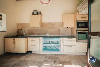 a kitchen with wooden cabinets and a stove top oven at Villa le Thor Piscine Billard Sauna et Jacuzzi in Le Thor