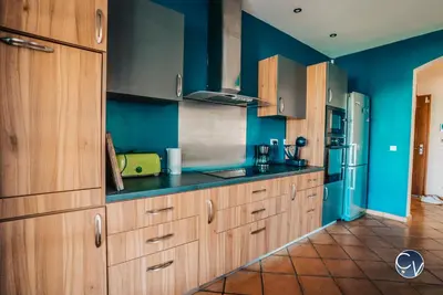 a kitchen with blue walls and wooden cabinets at Villa le Thor Piscine Billard Sauna et Jacuzzi in Le Thor