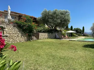 a stone house with a yard with a swimming pool at In Gordes, facing the entire Luberon Park a beautiful 5 bedrooms house in Gordes