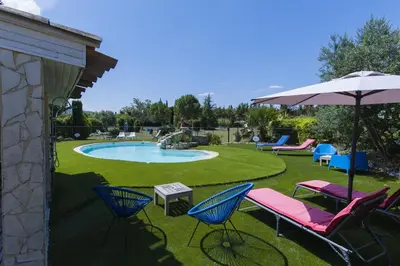 a patio with chairs and an umbrella and a pool at Gite Grand Luberon chez Manon en Luberon - Vacation rental in guest house in Lagnes