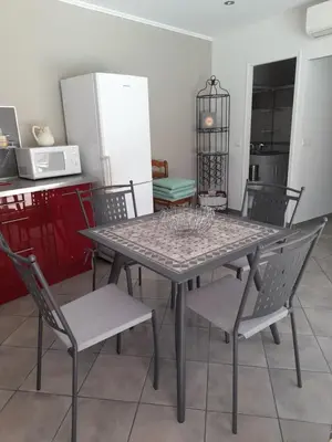 a table and chairs in a kitchen with a refrigerator at Villa le Bosquet en Luberon. in Ménerbes