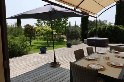 a table with an umbrella on a wooden deck at Bastide Magnolia - Gite et chambres d 'hôtes Les dépendances, Roussillon in Roussillon