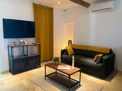 a living room with a couch and a table at Le mas des glycines - parking privé et terrasse ombragée in Salon-de-Provence