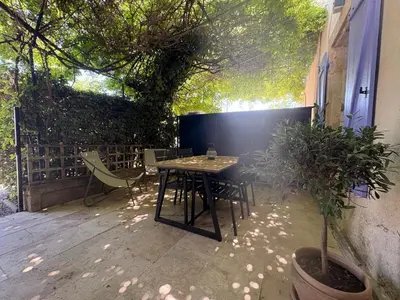 a patio with a table and chairs and a tree at Le mas des glycines - parking privé et terrasse ombragée in Salon-de-Provence