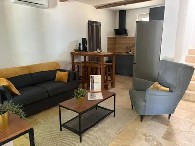 a living room with a couch and a chair and a table at Le mas des glycines - parking privé et terrasse ombragée in Salon-de-Provence