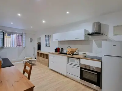 a kitchen with white appliances and a wooden table at T2 Centre Historique Rénové in Aix-en-Provence
