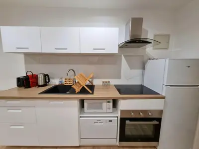 a kitchen with white cabinets and a white refrigerator at T2 Centre Historique Rénové in Aix-en-Provence