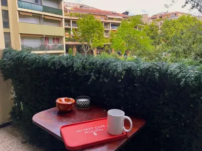a table with a book and two cups on it at Studio au cœur d'Aix avec balcon et parking in Aix-en-Provence