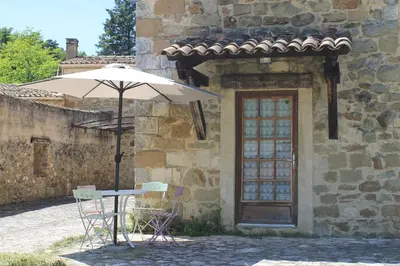 a table and chairs under an umbrella in front of a building at L' ABBADIE in Carniol