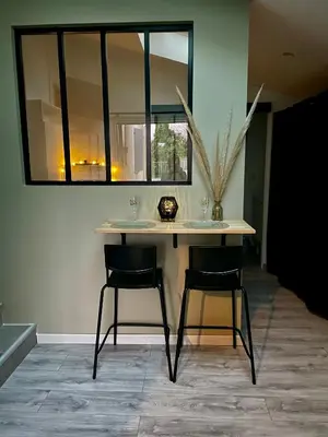 a table with two chairs in a room with a window at Studio climatisé et tout équipé in Saint-Didier