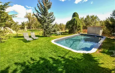a swimming pool in a yard with two chairs at Gorgeous Home In Sault in Sault-de-Vaucluse