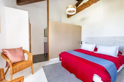 a bedroom with a large bed and a chair at La Bastide des Joncquiers in LʼIsle-sur-la-Sorgue