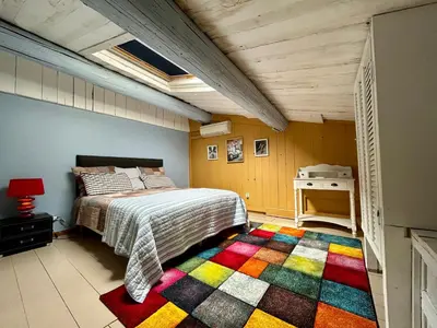 a bedroom with a bed and a colorful rug at UN MOMENT SUSPENDU in Aix-en-Provence