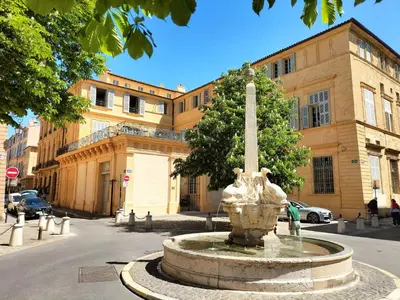 a fountain in the middle of a street in front of a building at CORDELIERS MAIRIE in Aix-en-Provence